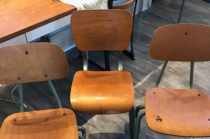 Three empty, old-fashioned school chairs