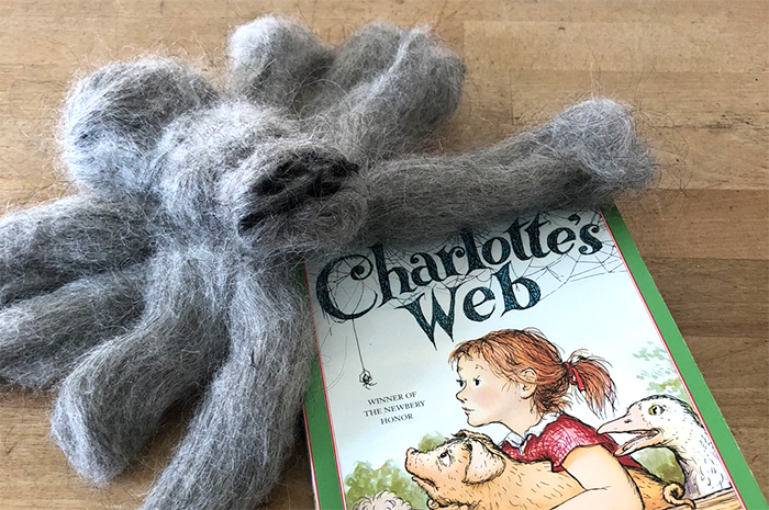 Large spider made out of wool next to copy of Charlotte's Web book
